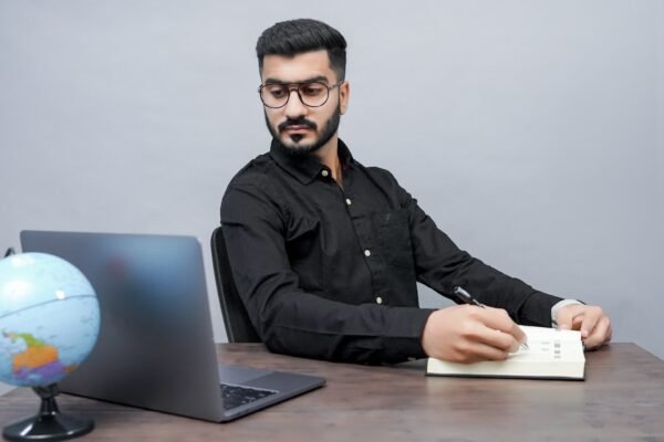 a man sitting at a desk with a laptop and a globe